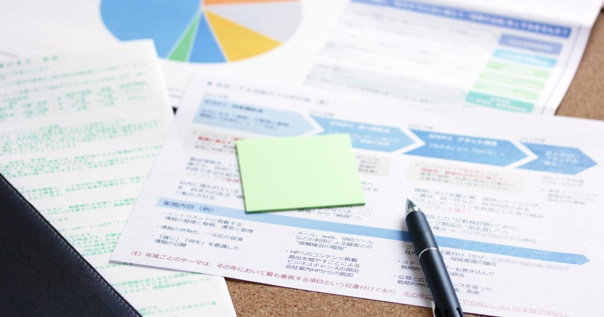 資金の計画書の上にあるメモとペン