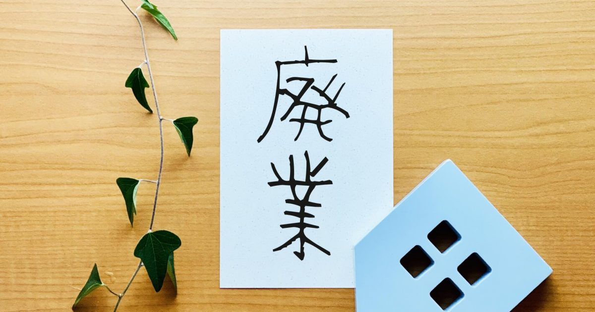 廃業と書いた紙と模型の家