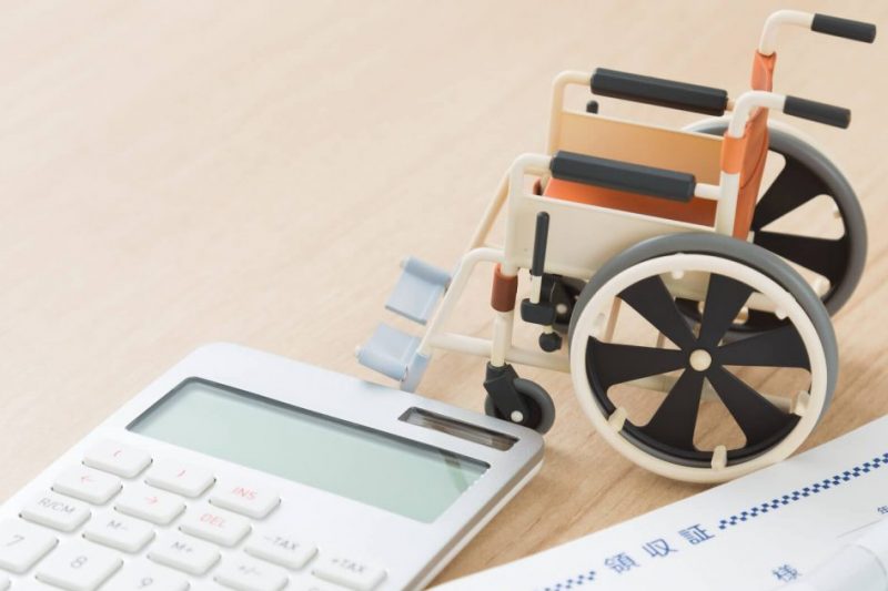 車椅子の模型と医療費の領収証