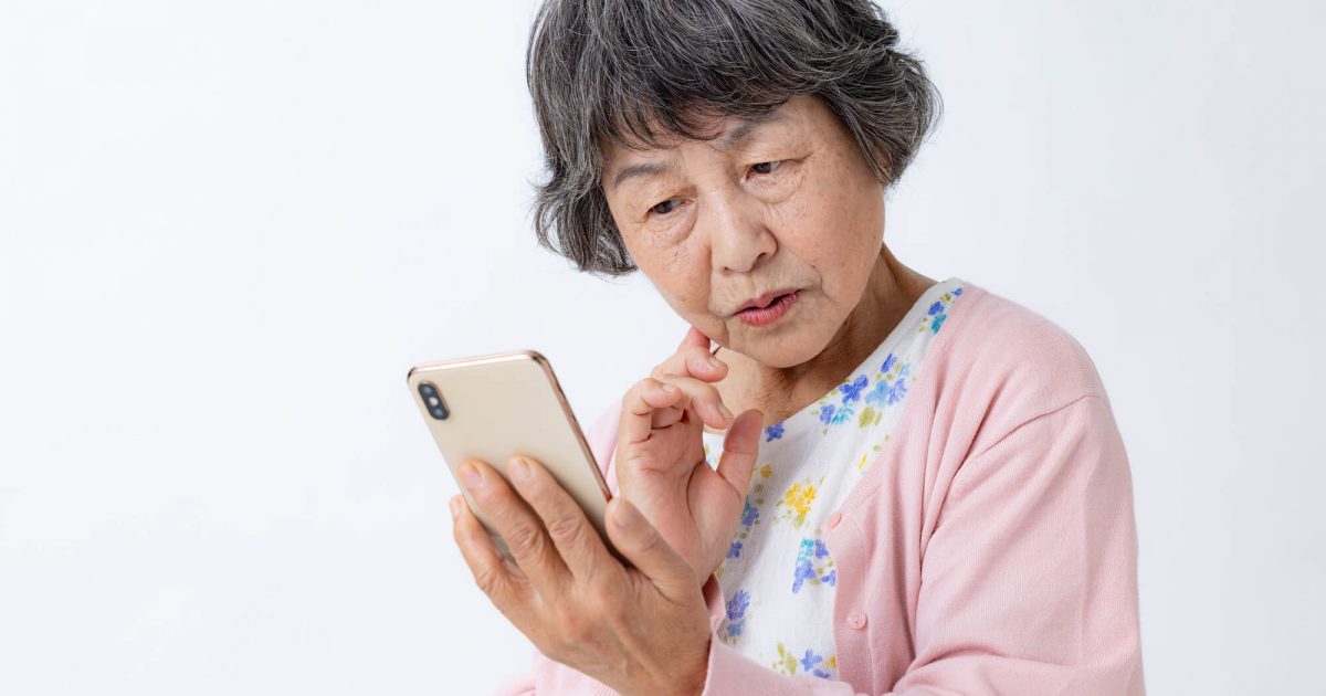 スマホをみて首をかしげるシニア女性
